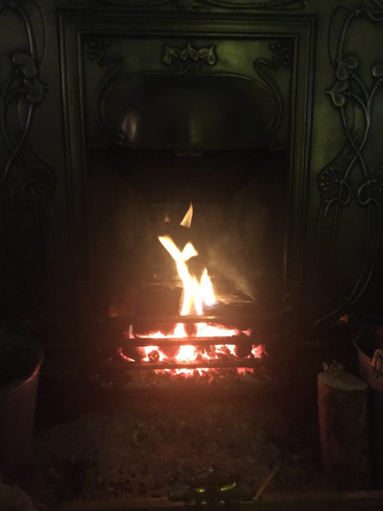 Open fire burning in the living room of Priory Cottage